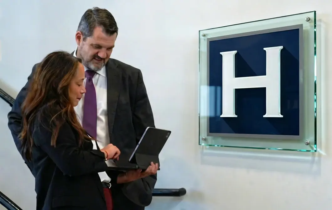 Una foto de Tommy Hastings y un miembro del personal mirando una tableta en la que se muestran los testimonios de clientes recibidos recientemente por su bufete de abogados especializado en negligencia médica.