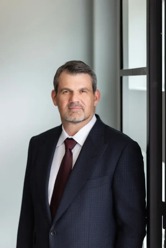 A photo of trial attorney Tommy Hastings in suit and tie, standing outside a settlement proceeding.